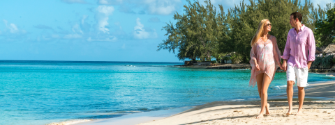 The image features a man and a woman walking hand in hand along a beautiful beach