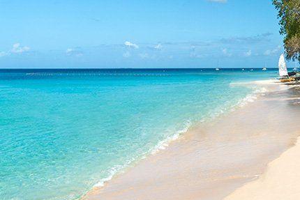 This image shows a beautiful beach scene with clear turquoise water and a serene sandy shore