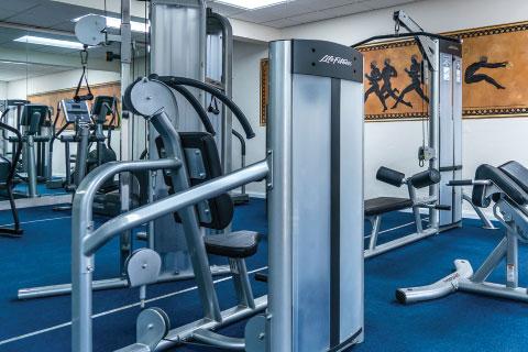 The image shows the interior of a gym with various types of exercise equipment