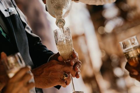 This image shows a person pouring champagne into a champagne flute held by another person