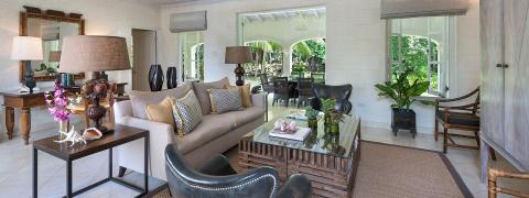 The image shows a stylish and well-decorated interior room with a seamless flow into an outdoor patio area