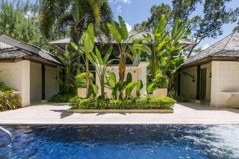 This image shows an attractive outdoor scene featuring a swimming pool bordered with a stone deck