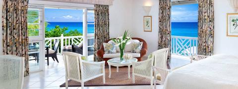 The image shows a beautifully decorated room that opens up to a scenic ocean view