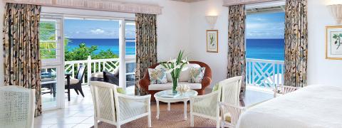 This image features a brightly lit, elegantly decorated room with a tropical beach view