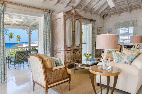 This image shows a stylishly decorated interior room of a house with a view of the ocean through a balcony door