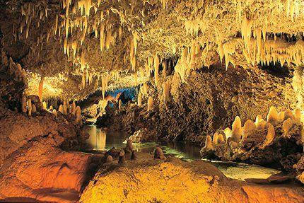 This image shows the interior of a cave with numerous stalactites hanging from the ceiling and stalagmites rising from the ground, creating an intriguing natural formation