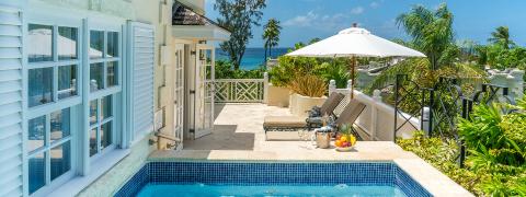 The image shows a luxurious outdoor patio area by the sea