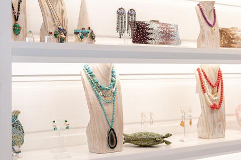 The image shows an elegantly arranged display of fashion accessories on white shelves