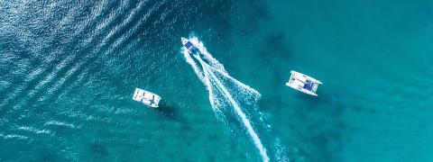 This image shows an aerial view of three boats on a body of water, likely a sea or ocean