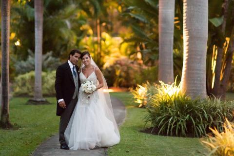 The image captures a bride and groom in a beautiful outdoor setting, likely in a garden or park