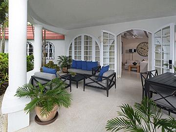 The image shows a covered patio area with an outdoor living setup