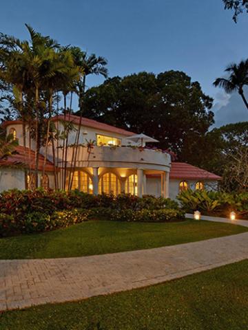 The image shows a large, elegant house during twilight