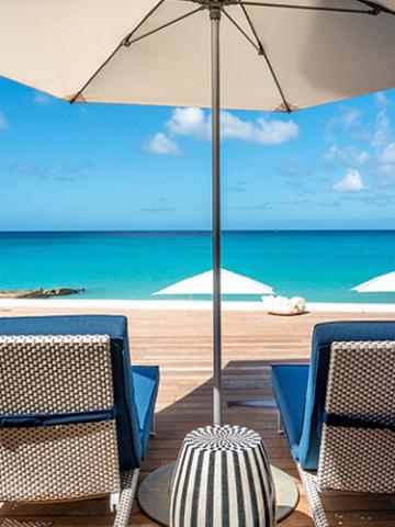 This image features a serene beach view from a seaside deck