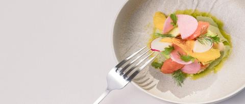 This image features an elegantly plated dish that includes various thinly sliced fruits and vegetables, possibly a salad