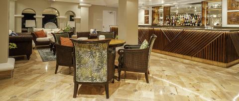 The image depicts a stylish indoor lounge area featuring a bar on the right side