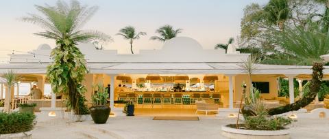 This image features an elegant outdoor bar and seating area set in a tropical location