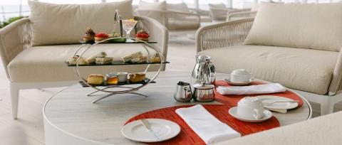 The image depicts a luxurious afternoon tea setup likely in an outdoor or patio setting of a cafe or hotel