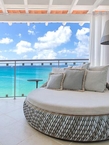 This image shows a luxurious patio or balcony space overlooking a beautiful beach