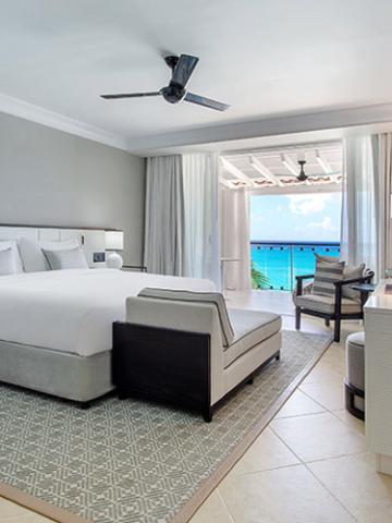 This image shows a stylish hotel or resort room with a scenic ocean view