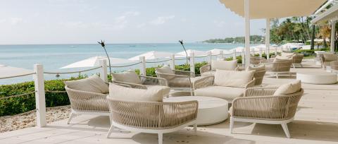 This image features a luxurious outdoor lounge area overlooking a beach
