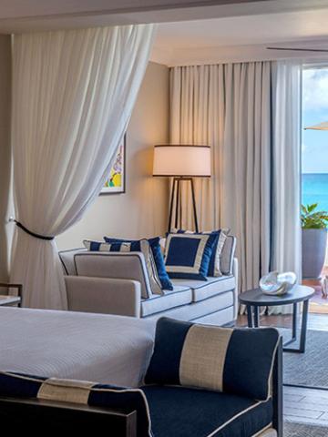 This image shows a well-appointed hotel room or a resort suite with a luxurious, coastal decor theme