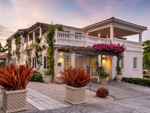 This image shows a beautifully landscaped exterior of a two-story house at dawn or dusk