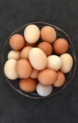 The image shows a collection of eggs in a metal basket on a dark grey surface