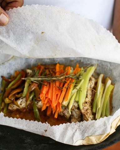 This image shows a dish that appears to be a type of en papillote meal, where fish or another protein, along with vegetables, is cooked inside a parchment paper packet
