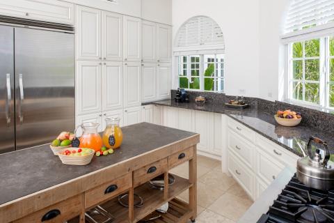 This image shows a well-lit, spacious kitchen with white cabinetry and dark granite countertops