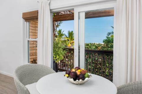 This image depicts a bright, airy room with a view looking out to a tropical scenery