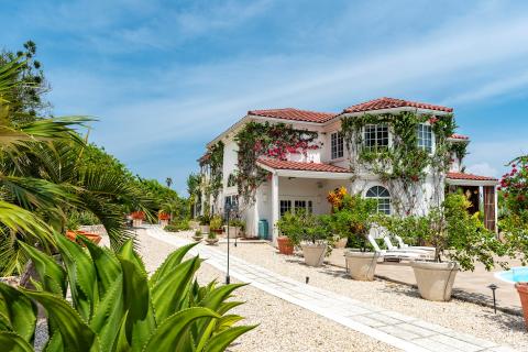 This image depicts a beautiful and luxurious two-story home adorned with lush foliage and flowers