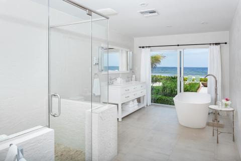 This image shows a modern, luxurious bathroom with an oceanfront view