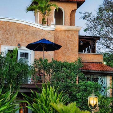 The image features a charming and picturesque building, likely a residential villa or a small hotel