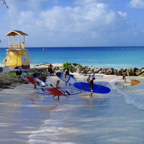 This image captures a vibrant beach scene where individuals, including adults and children, are engaged in water sports