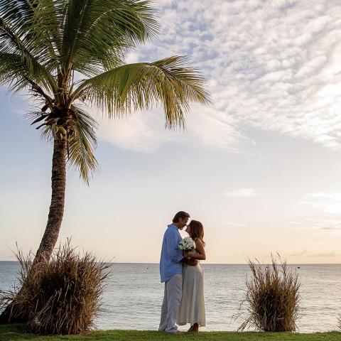 This image captures a romantic scene of a couple standing close to each other near a beach