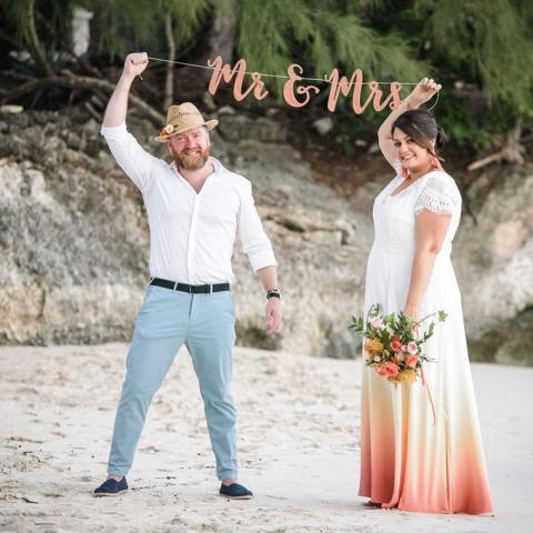 This image features a couple celebrating on a sandy beach