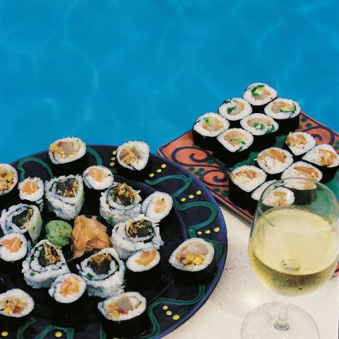 The image shows two plates full of various types of sushi, served near a pool