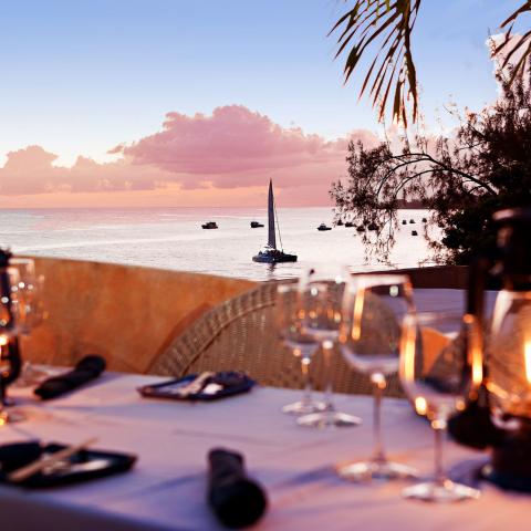 This image captures a serene and picturesque setting at a beachside restaurant during sunset