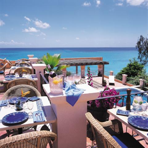 This image shows an inviting terrace set up for dining with a fantastic view of the ocean
