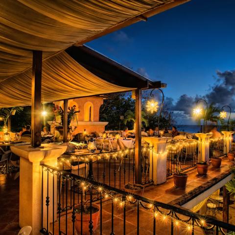 This image shows a beautifully lit outdoor dining area at dusk