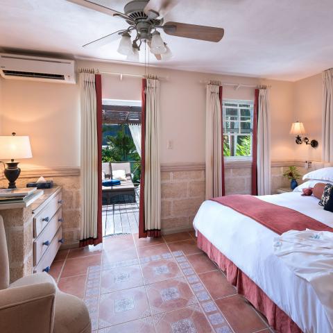 The image depicts a cozy and elegantly decorated bedroom in what appears to be a tropical resort setting