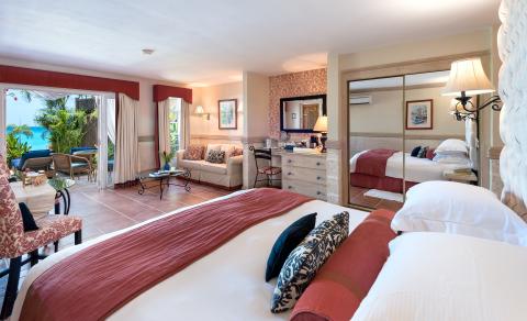 This image shows a luxurious bedroom that opens out onto a beautiful tropical landscape, which includes a view of the ocean