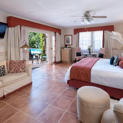 This image features a spacious and well-decorated bedroom leading out to a pool area