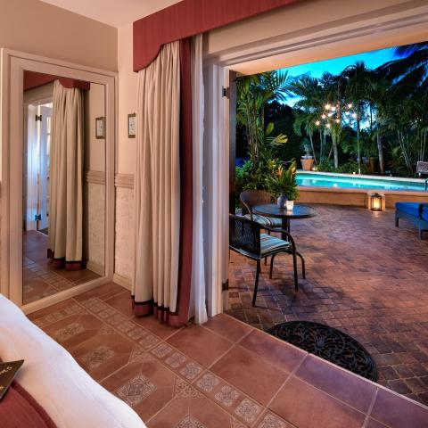 The image displays a beautifully appointed room leading to an outdoor patio area