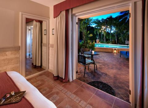 The image shows a well-appointed room leading out to a patio area with a swimming pool