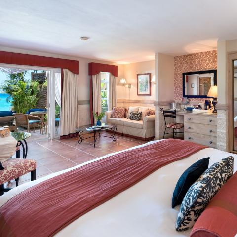 This image shows a luxurious and spacious hotel room with direct views of the ocean