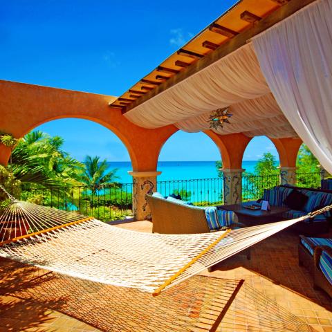 This image depicts a luxurious outdoor terrace with a beautiful ocean view