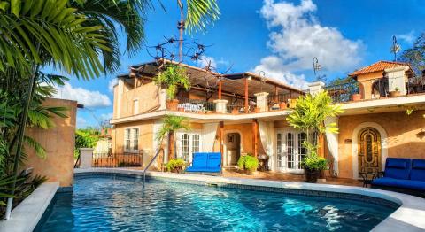 The image shows a luxurious backyard setting with a Mediterranean-style house
