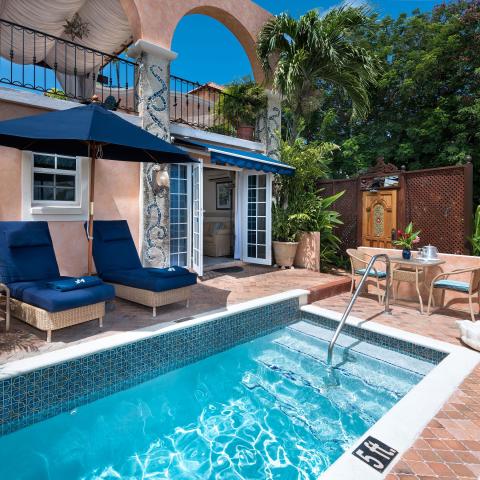 The image features a cozy outdoor space with a small rectangular swimming pool surrounded by brick tiles