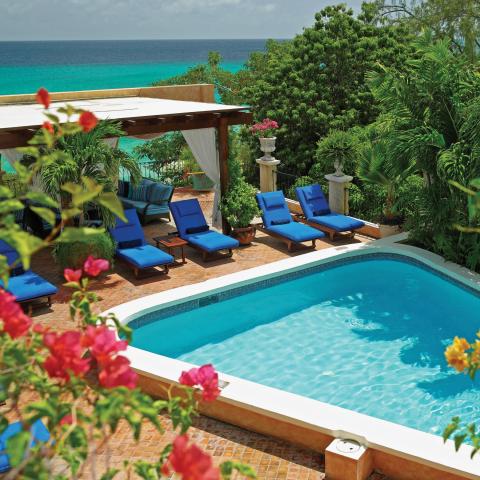 The image showcases a picturesque outdoor setting with a swimming pool and a view of the sea